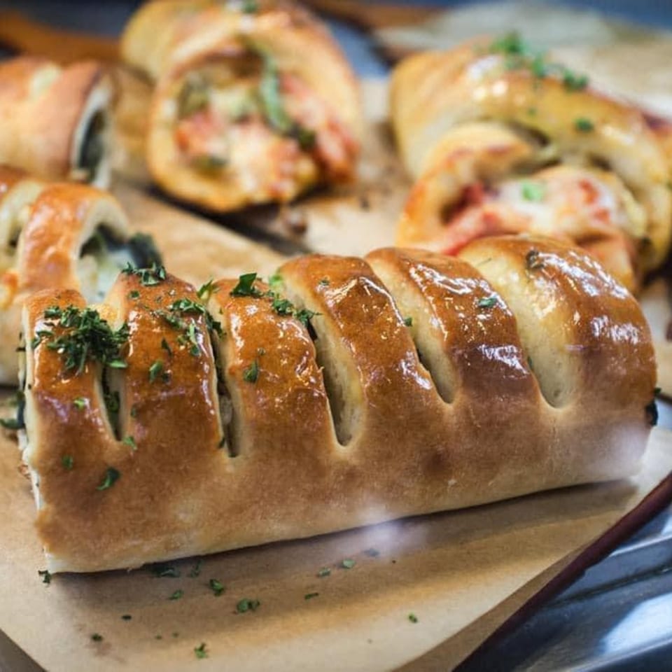 Freshly baked stromboli with golden crust and herbs, displayed on parchment paper at Capri's Pizzeria.