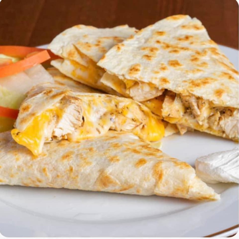 Chicken quesadillas with melted cheese, served with a side of sour cream and salad.